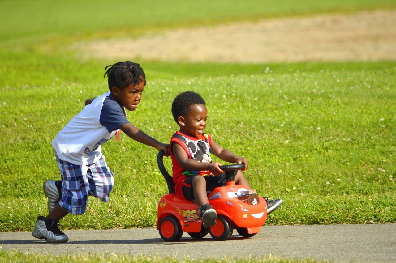 One African American Child pushing a cart with a smaller child riding