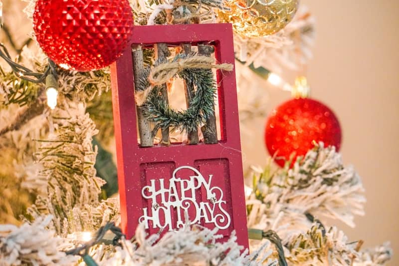 a christmas tree with ornaments and a red door