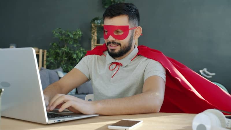 Man in superhero costume working on a laptop.