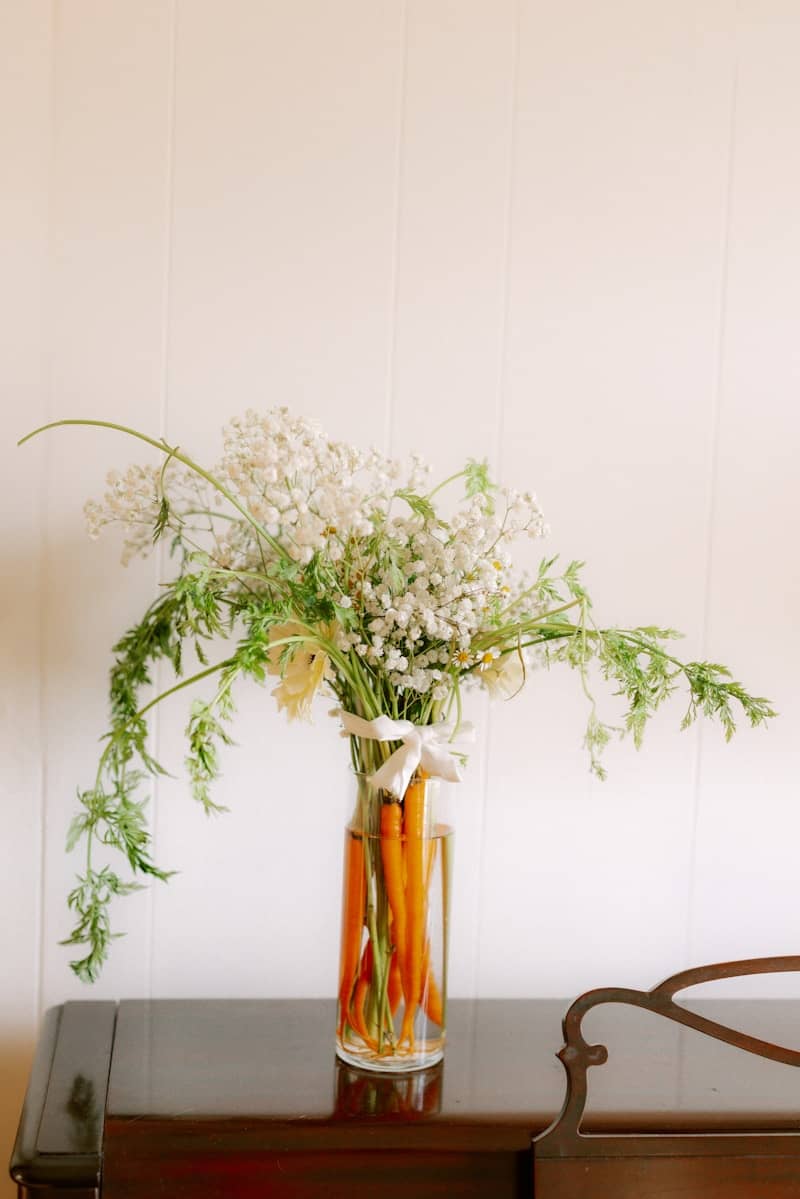 Carrots and white flowers in a glass vase