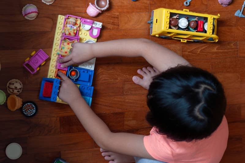 A child plays with colorful toys on a wooden floor