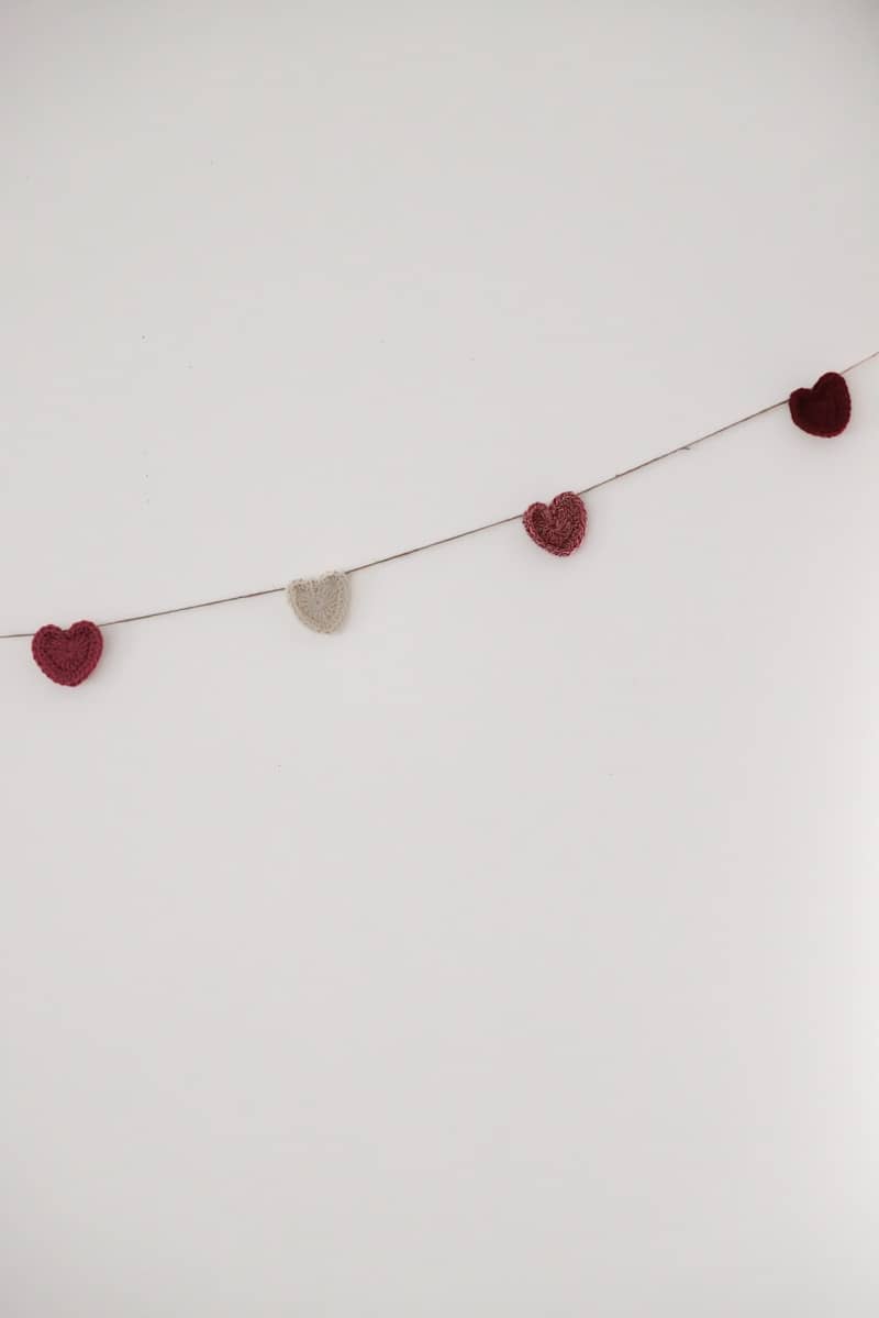 A string of small heart-shaped decorations hangs against a wall.