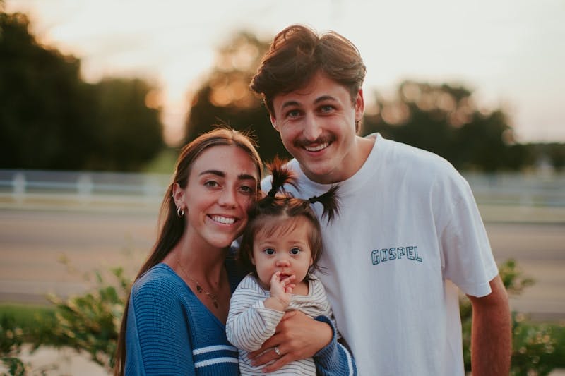 A man and a woman pose for a picture with a baby