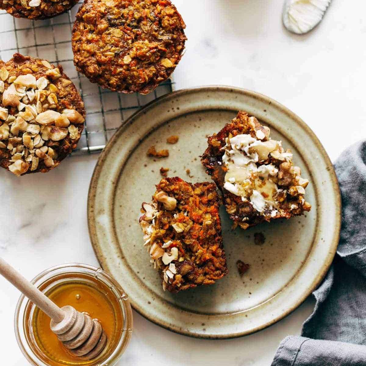 Carrot muffin on a plate with honey on the side and a smear of butter
