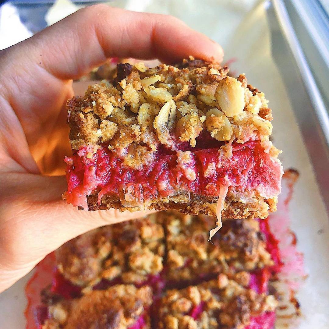 Strawberry crumble bars being held by white handd