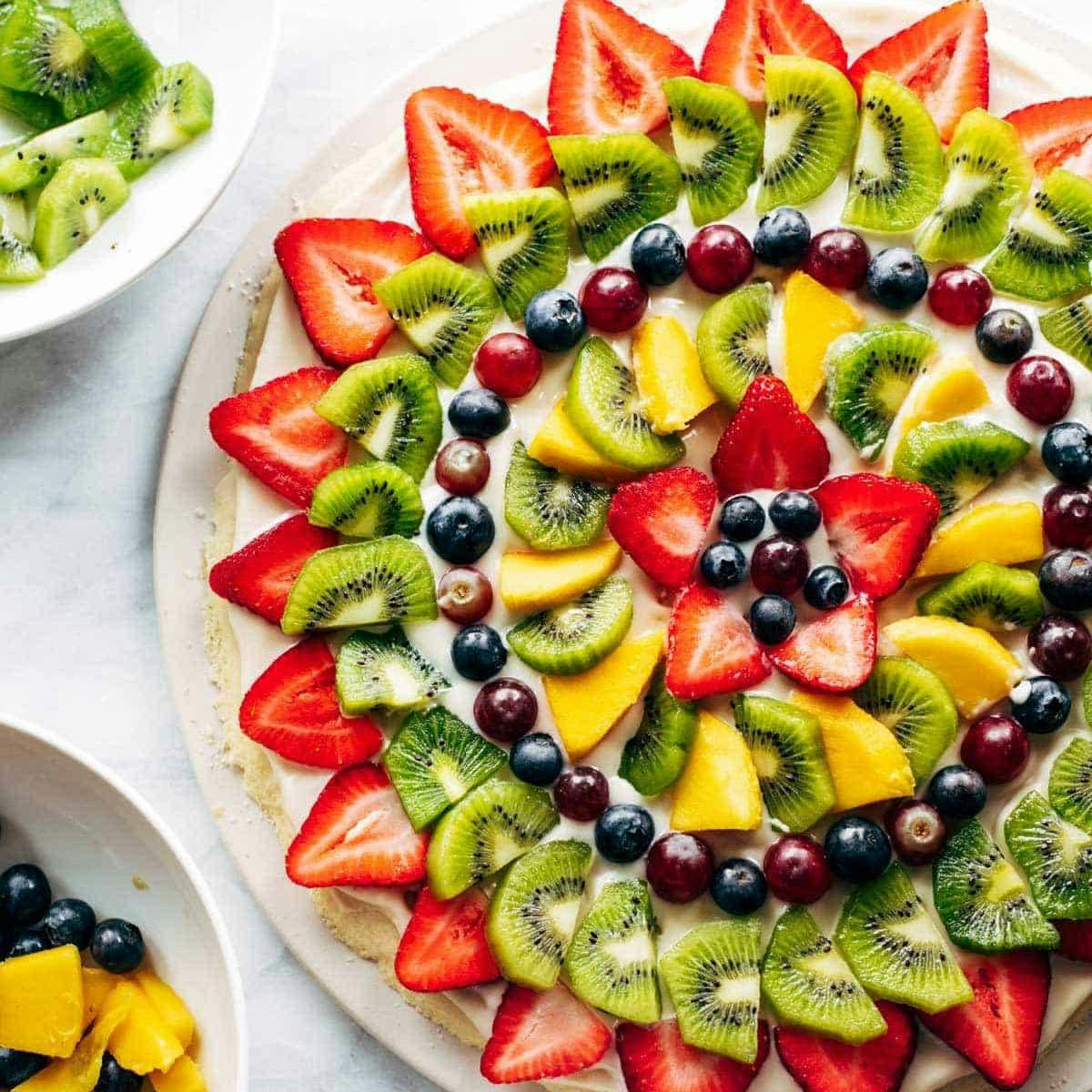 Fruit pizza with strawberries, grapes, mango, and kiwi.
