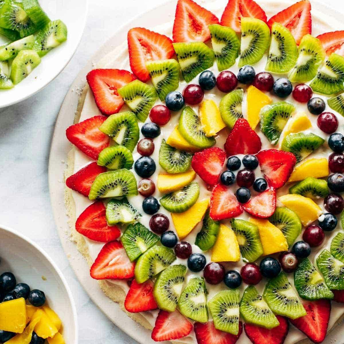 Fruit pizza with strawberries, grapes, mango, and kiwi.