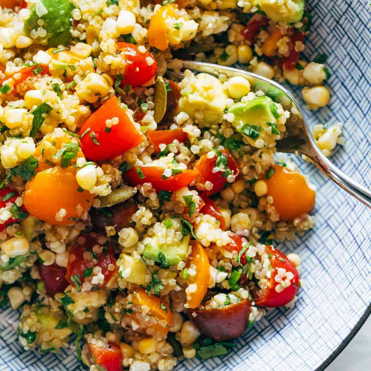 Corn, avocado, quinoa salad in a bowl with marinated tomatoes.