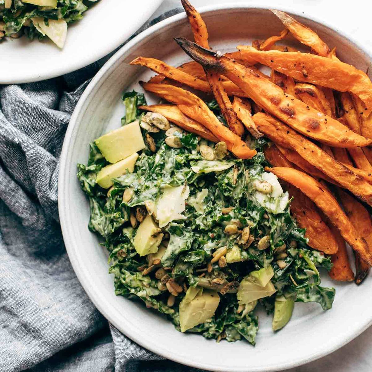 Vegan caesar salad on a plate with sweet potato fries