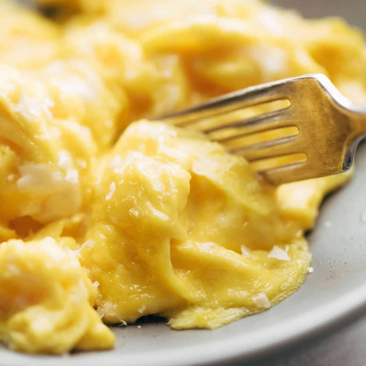 Fork cutting into soft scrambled eggs
