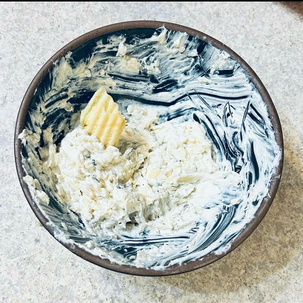 Onion dip in a blue bowl with a chip