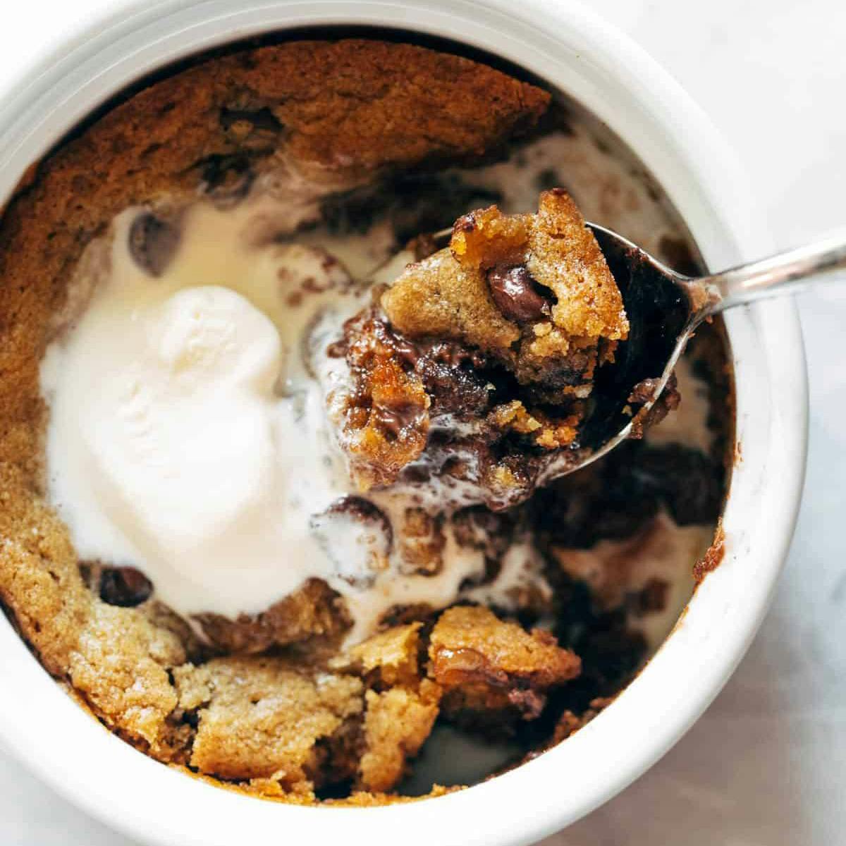 Spoon scooping bite out of cookie bowl with ice cream on top