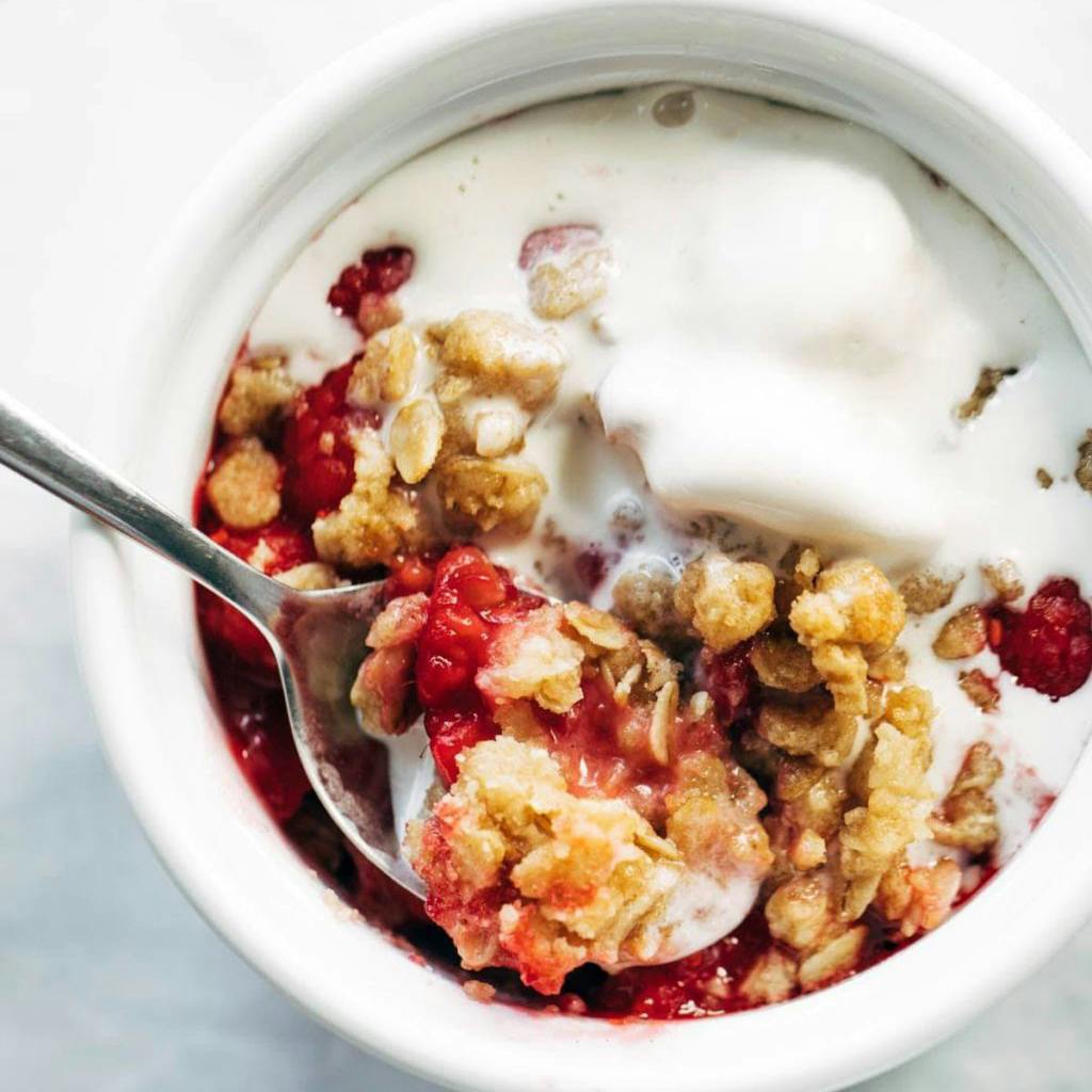 Raspberry crumble in a bowl with ice cream.