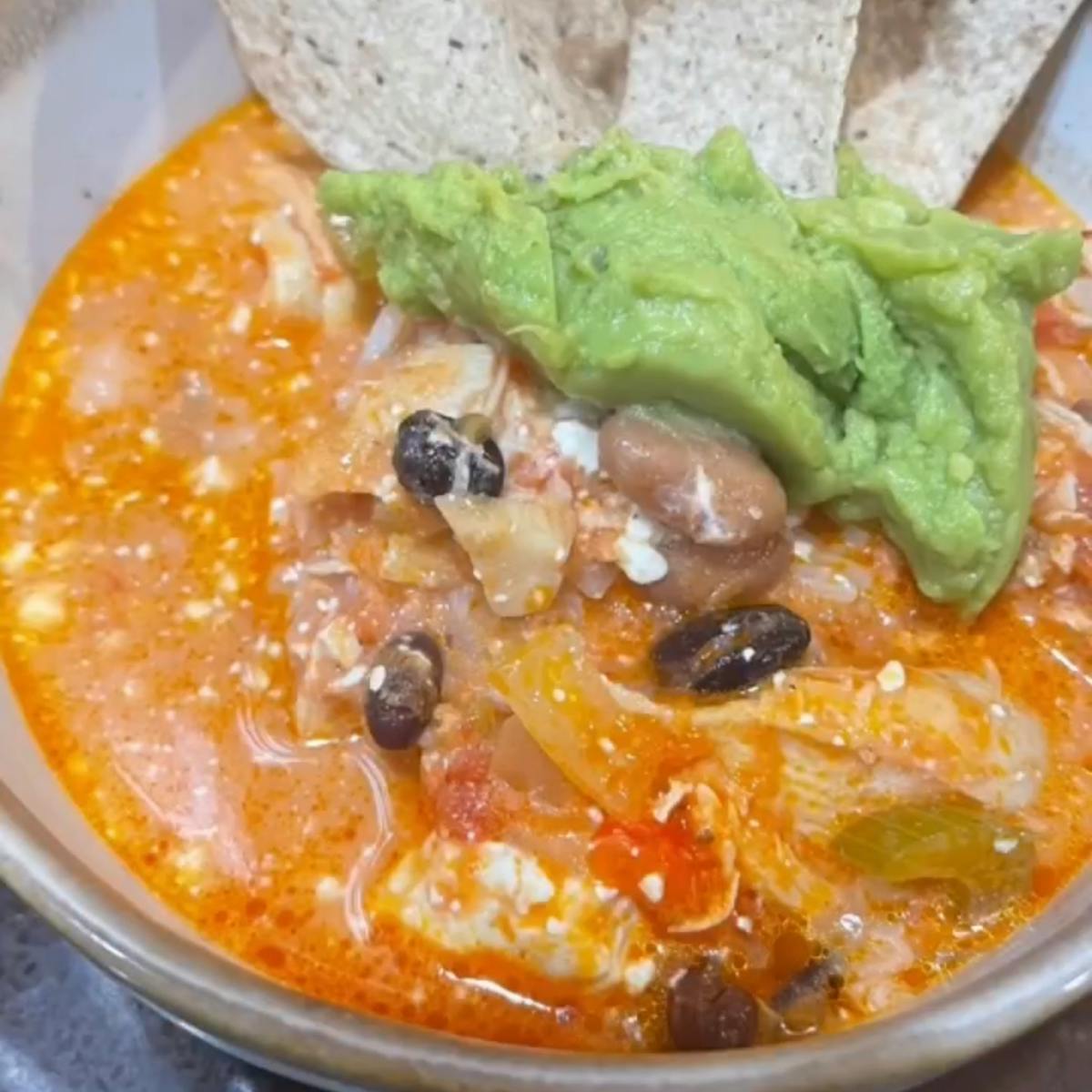 White chicken chili with guacamole on top and tortilla chips