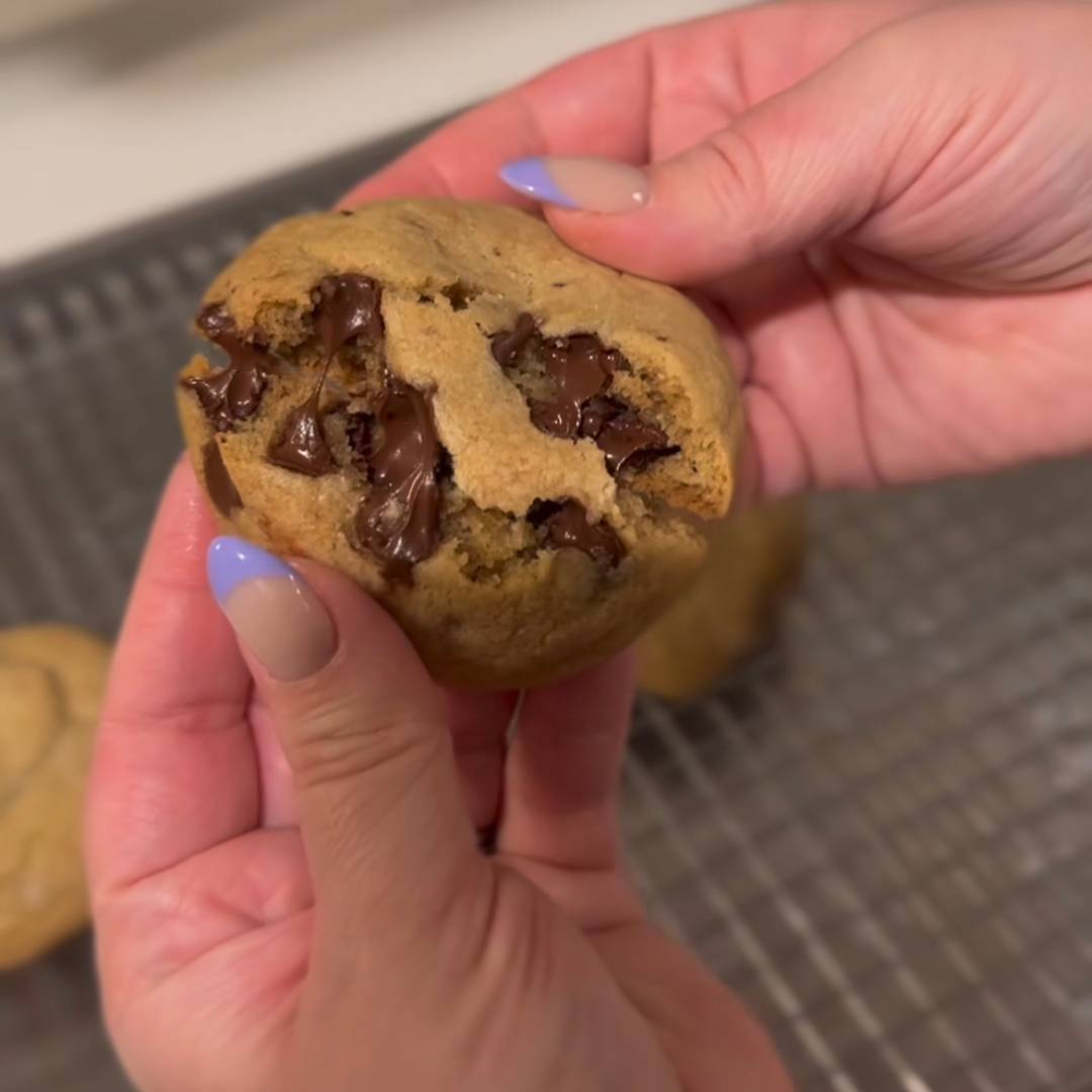 Hand breaking a chocolate chip cookie in half