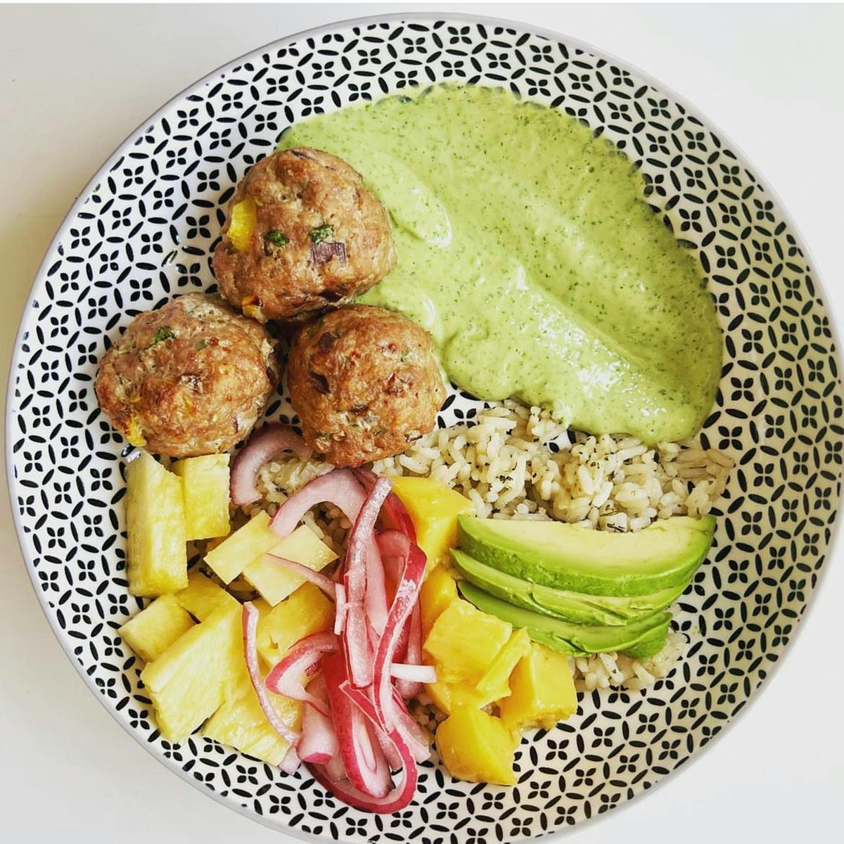 Meatballs, mojo sauce, fruit, and avocado in a bowl