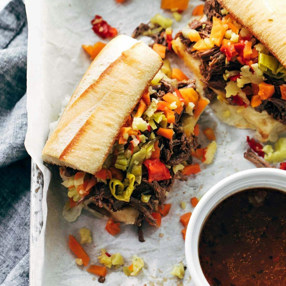 Italian beef sandwiches with au jus on parchment paper