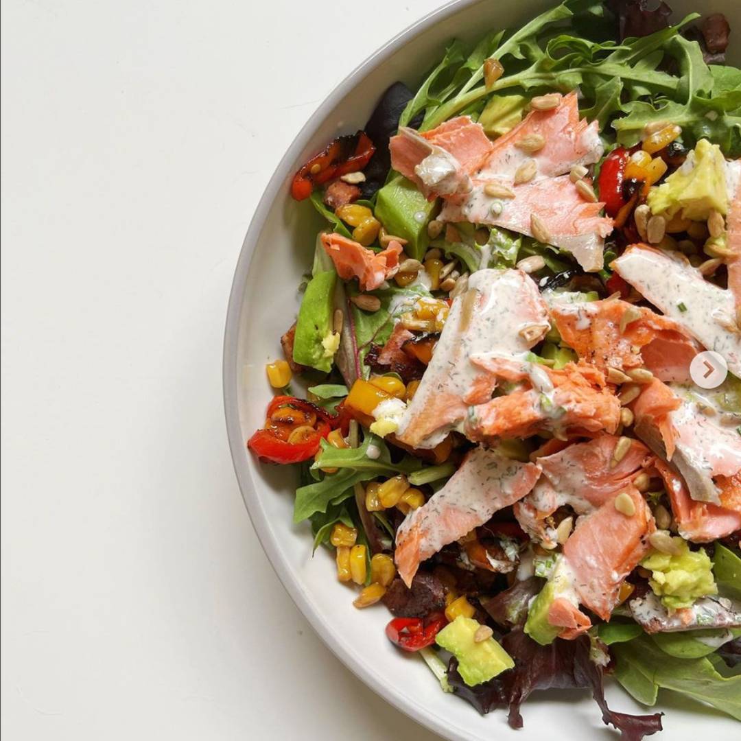 Salad with salmon and dressing on top.