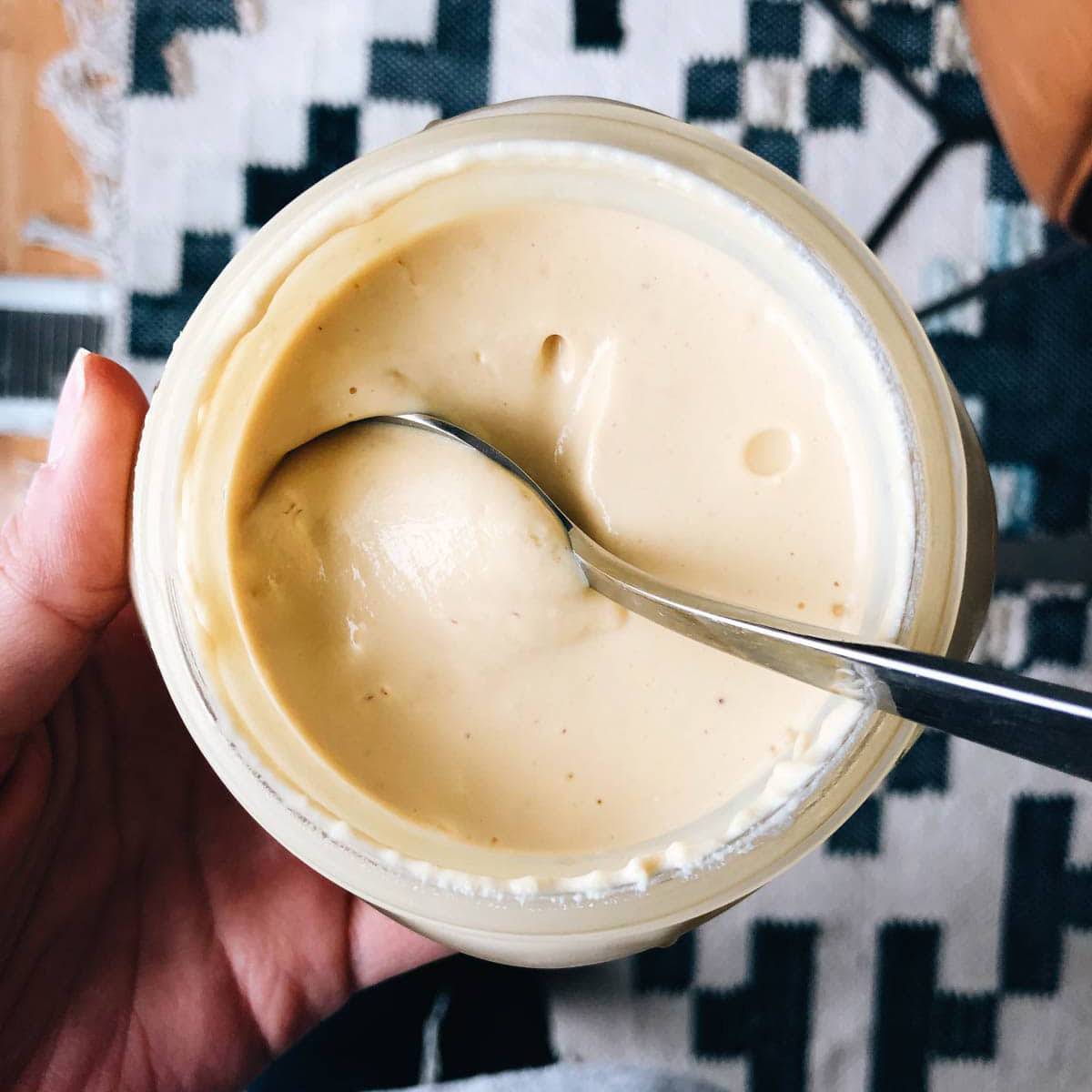 Vegan Yogurt in a jar with a spoon being held in one hand