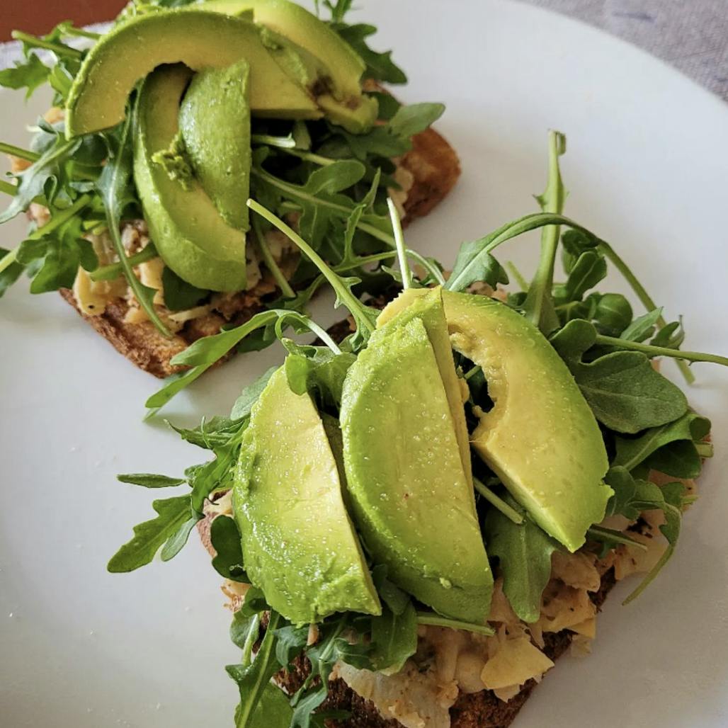 White bean artichoke toast on a plate with avocado.