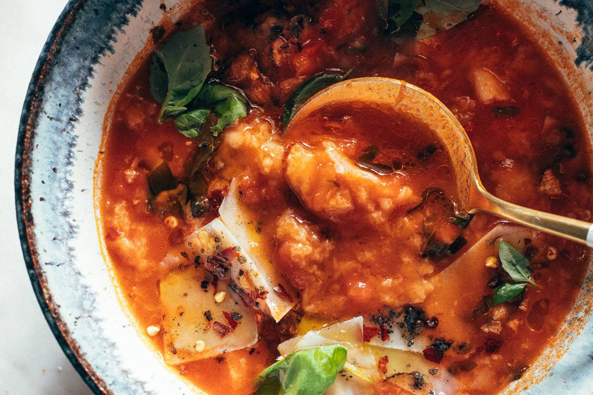 Gold spoon in a bowl with tomato and bread soup