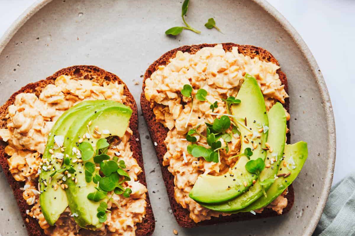 Spicy chickpea salad on toast topped with avocado on a plate