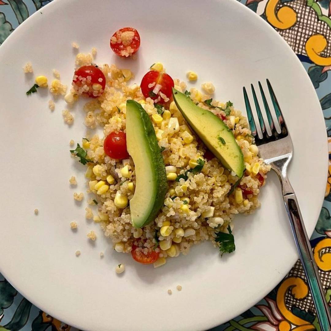 Corn, avocado, quinoa salad on a plate with a fork.