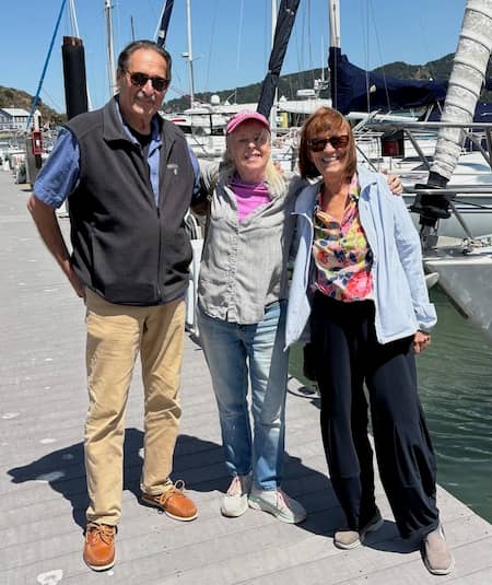The Women’s Eye Publisher Pamela Burke (m) with artist-designer Jim Shubin (l) and travel writer Laurie McAndish King (r) standing on the sailboat docks in Tiburon, CA | Photo: P Burke