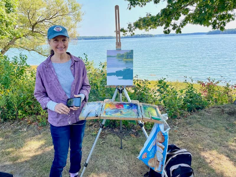 Artist Lisa Kyle with her easel on the riverbank painting the scene | Photo: P. Burke
