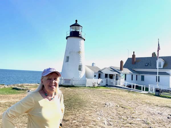 Pamela Burke   | Photo: P. Burke in front of a lighthouse in Permiquid, Mainee | Photo: P. Burke
