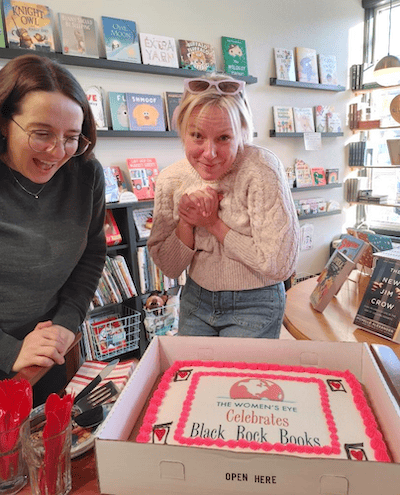  Black Rock Books co-owners, Meg Flynn(l) and Emily Welch (r), receiving a special cake and certificate from The Women’s Eye honoring the positive impact they are having in their community. The Women’s Eye honors a new individual or organization each year on Valentine’s Day | The Women’s Eye | thewomenseye.com