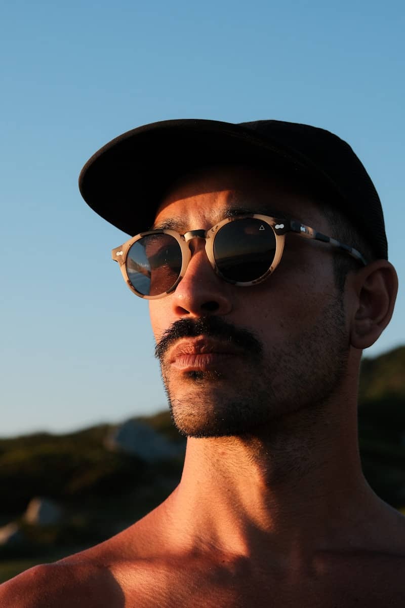 Man with sunglasses and cap against the sky