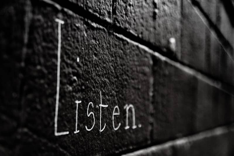 a black and white photo of the word listen written on a brick wall