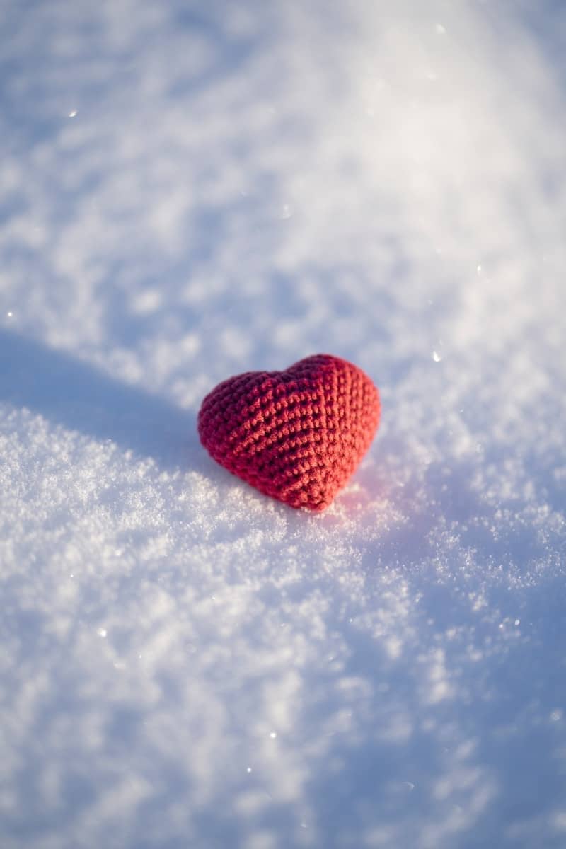 A red knitted heart sitting in the snow