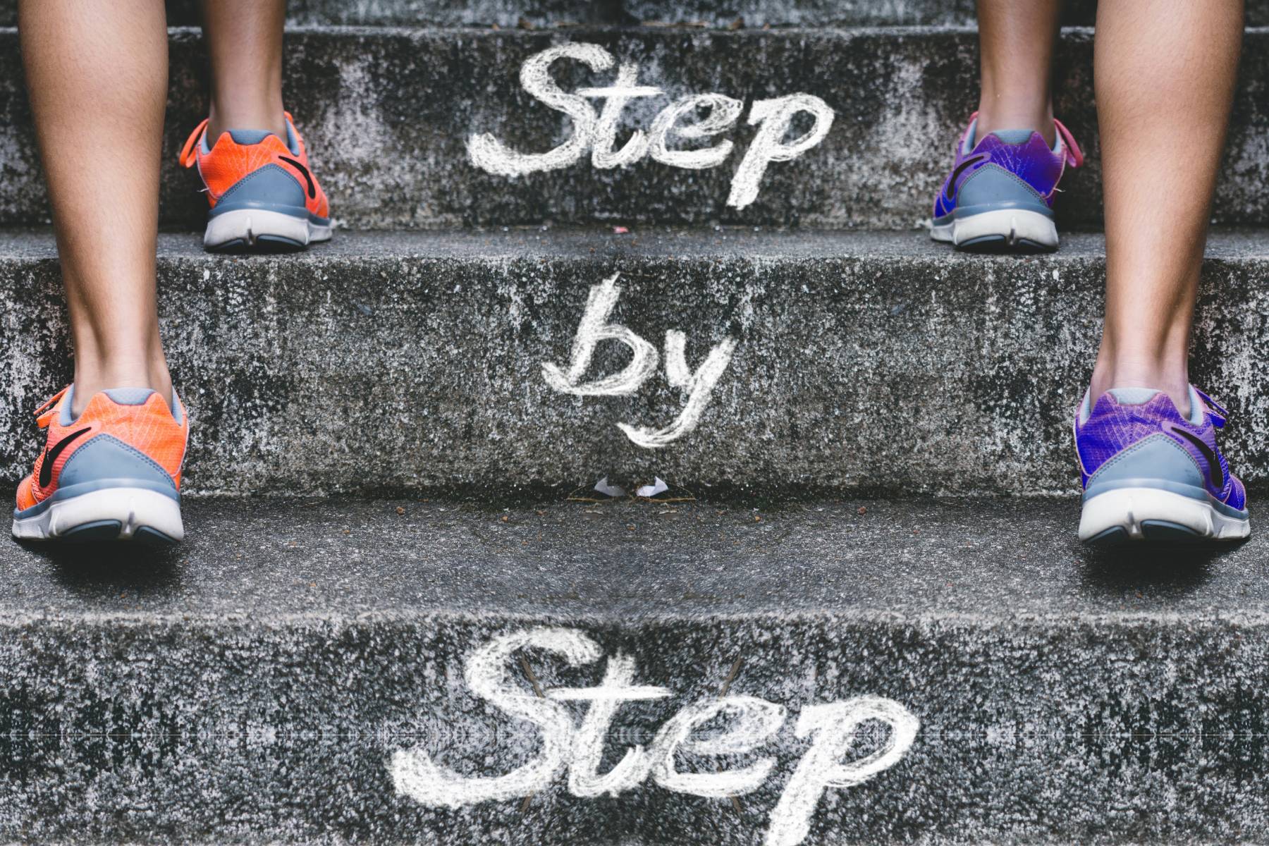 Two women walking up a staircase marked 'step by step,' symbolizing progress through small actions.
