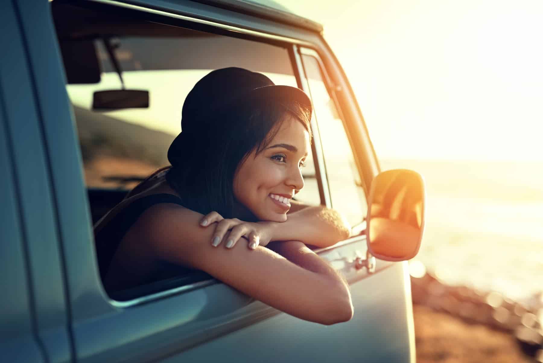 A young woman who understands the importance of self-worth enjoys a relaxing road trip, sitting in a van and watching the sunset.
