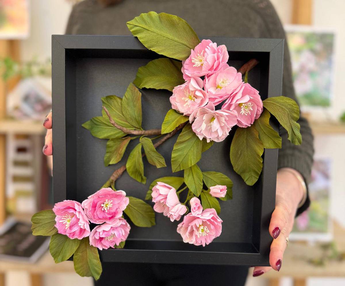 hands holding a finished, framed blossom artwork piece