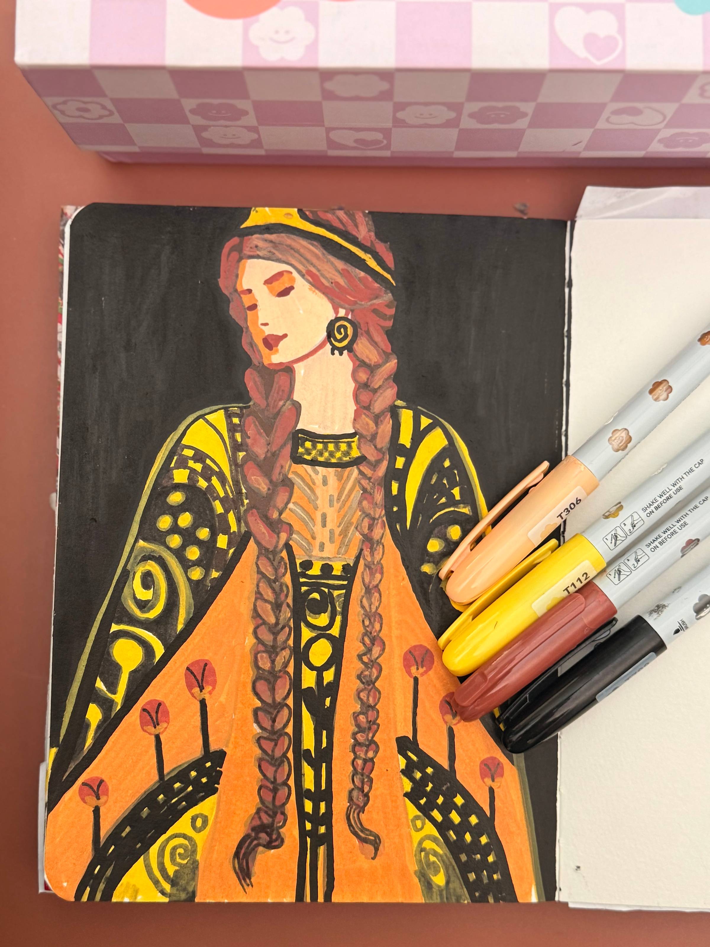 Colorful portrait of a woman in patterned clothing, with acrylic markers beside the artwork.