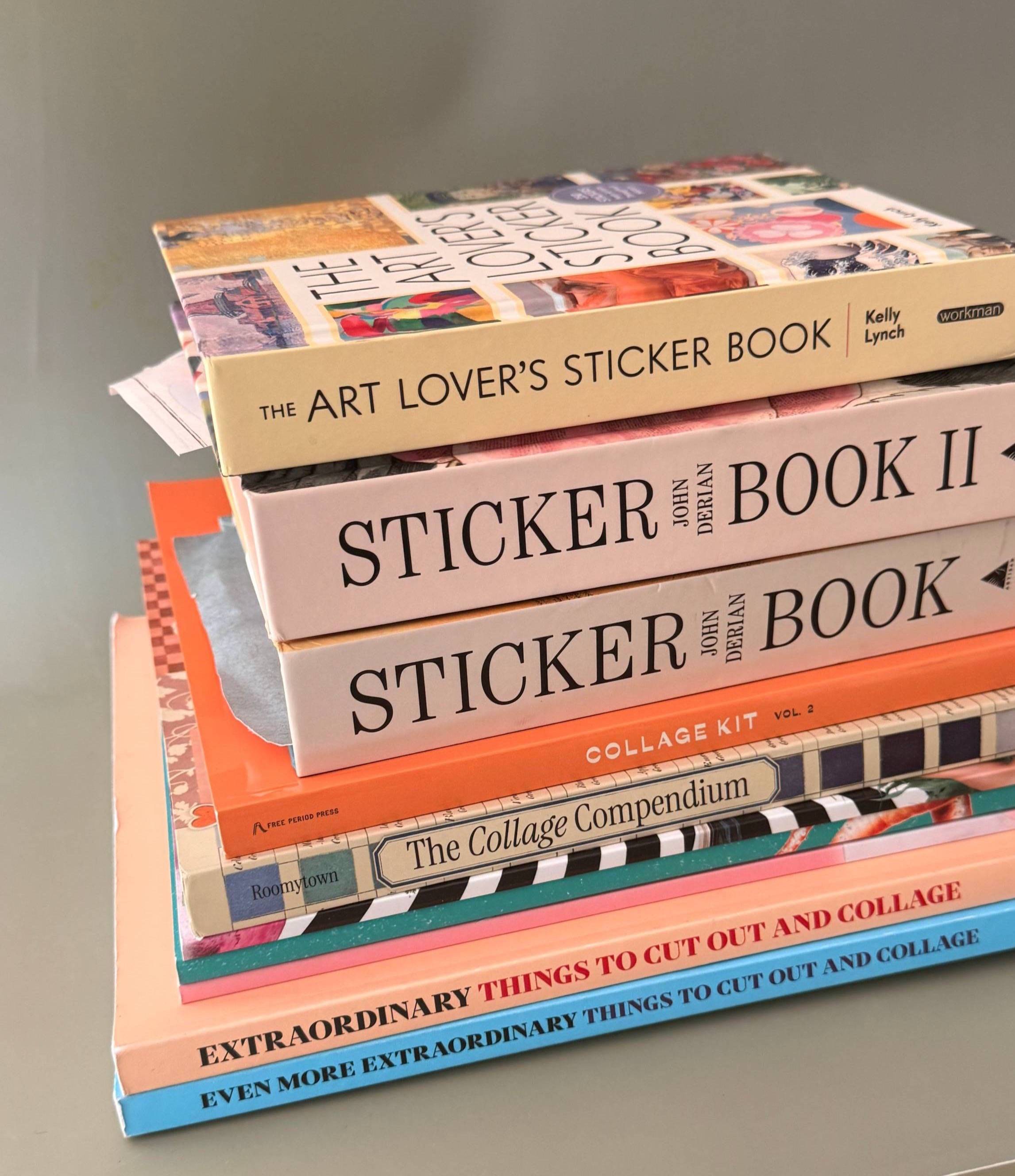 A colorful stack of sticker and collage books for Art Jounraling, piled up on my studio desk