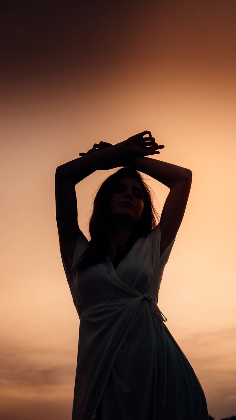 A woman in a white dress holding her hands up in the air