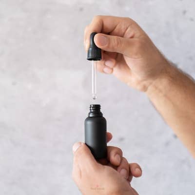 a man using homemade beard oil from a dropper bottle
