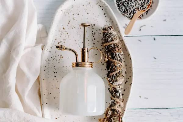 Spray bottle of essential oil smudge spray next to a sage smudge stick