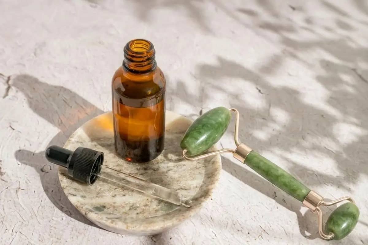 a bottle of diy facial massage oil and a jade roller