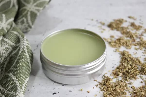 a tin of homemade oregano first aid salve for skin
