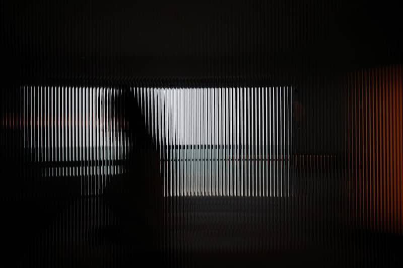 Blurred figure seen through a striped glass panel