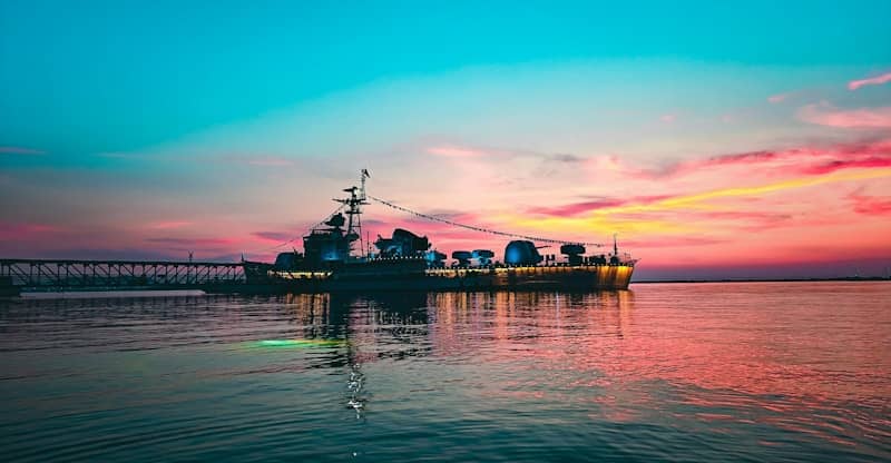 A large ship sails on the ocean at sunset.