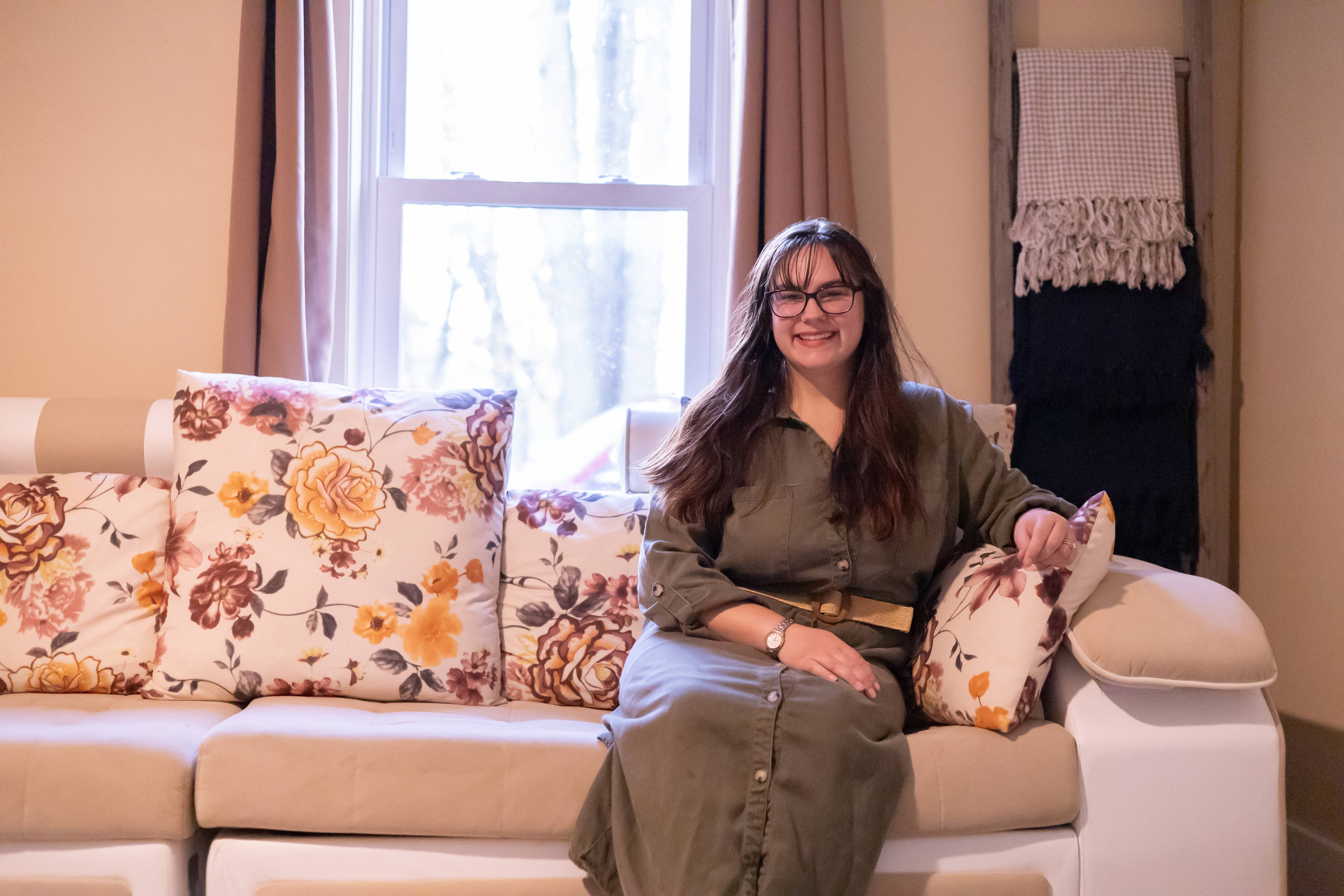 A picture of Micaiah Gray, the christian life coach at Reviving Christian Families, sitting on a couch and smiling