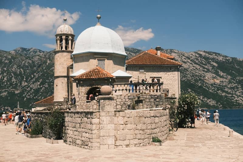 Island church with dome and bell tower near mountains