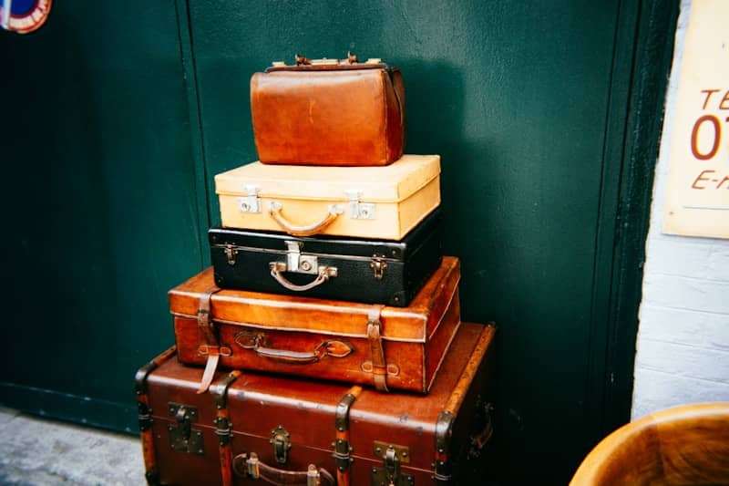 Stack of vintage suitcases against a dark green wall.