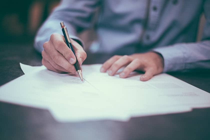 An image of a man at a desk, writing a business case